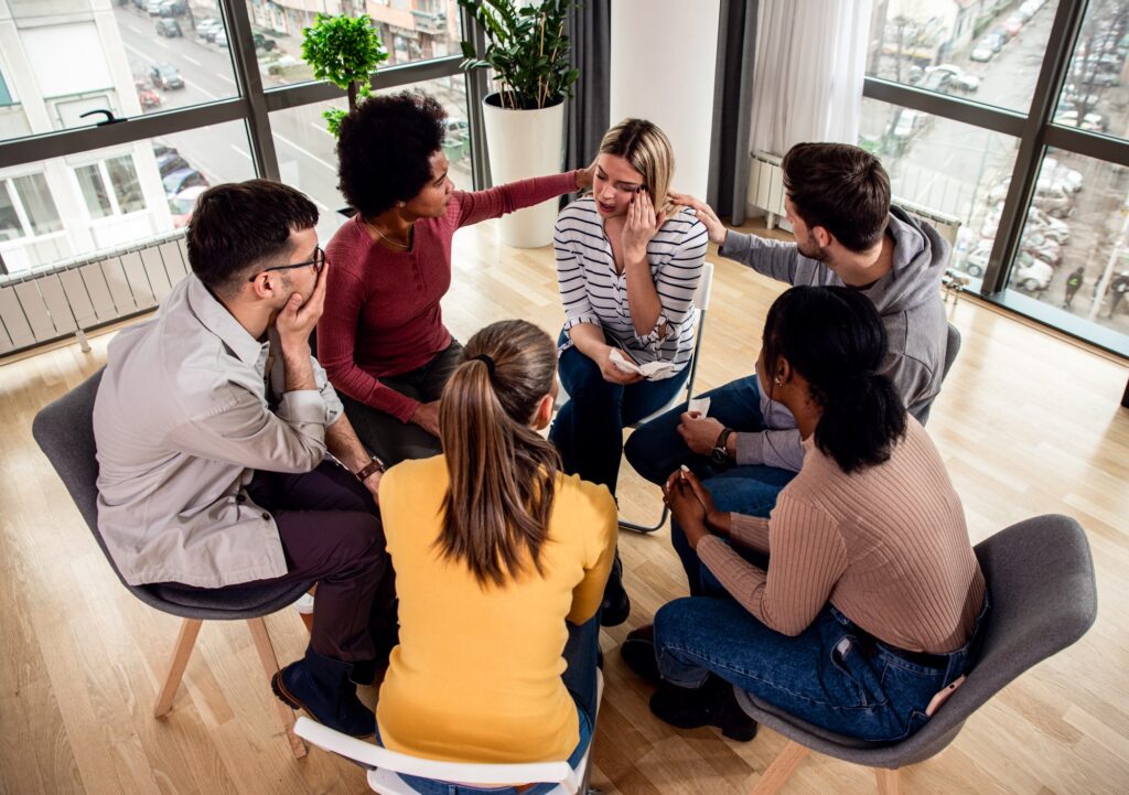Diverse group of people sitting in circle in group therapy session.